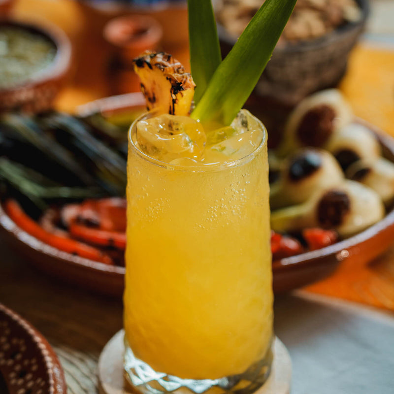 Charred Pineapple Margarita served over ice and garnished with a charred pineapple wedge.